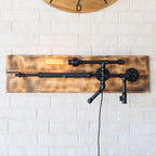 Wooden wall clock and decorative light fixture on a white brick wall.