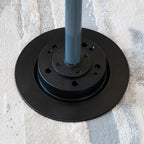 Black metal base with a gray pole on a textured surface