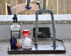 Bar setup with Jack Daniel's whiskey bottle, Coca-Cola can, and ice cubes on a stand.