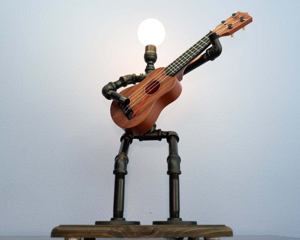 Ukulele lamp made from pipes with a light bulb on a white background