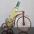 Wine bottle on a miniature bicycle decorative item against a plain background