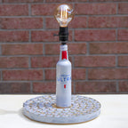 Lamp made from a Michelob Ultra beer bottle on a textured base against a brick wall.