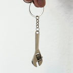 Metal wrench keychain held by a hand against a white background
