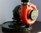 Red and black sander on a dark surface with a light blue wall background