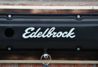Edelbrock logo on a black surface with a wooden background