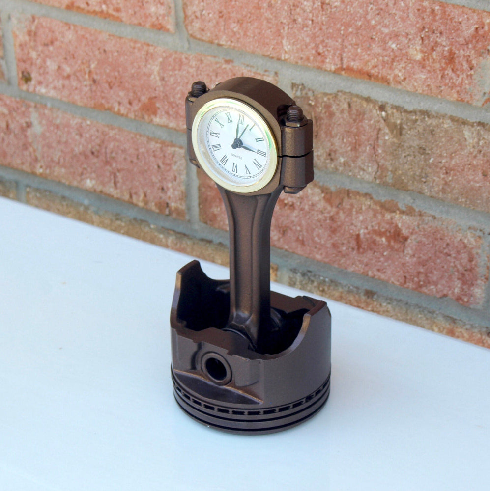 Automotive piston desk clock with functional quartz movement and side storage for office supplies.