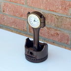 Automotive piston desk clock with functional quartz movement and side storage for office supplies.