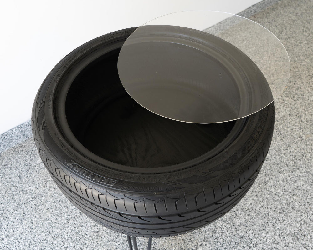 Bar height tire table featuring a flush plexiglass top and real recycled tire for smooth, functional automotive furniture.