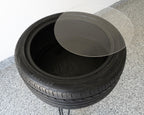 Bar height tire table featuring a flush plexiglass top and real recycled tire for smooth, functional automotive furniture.