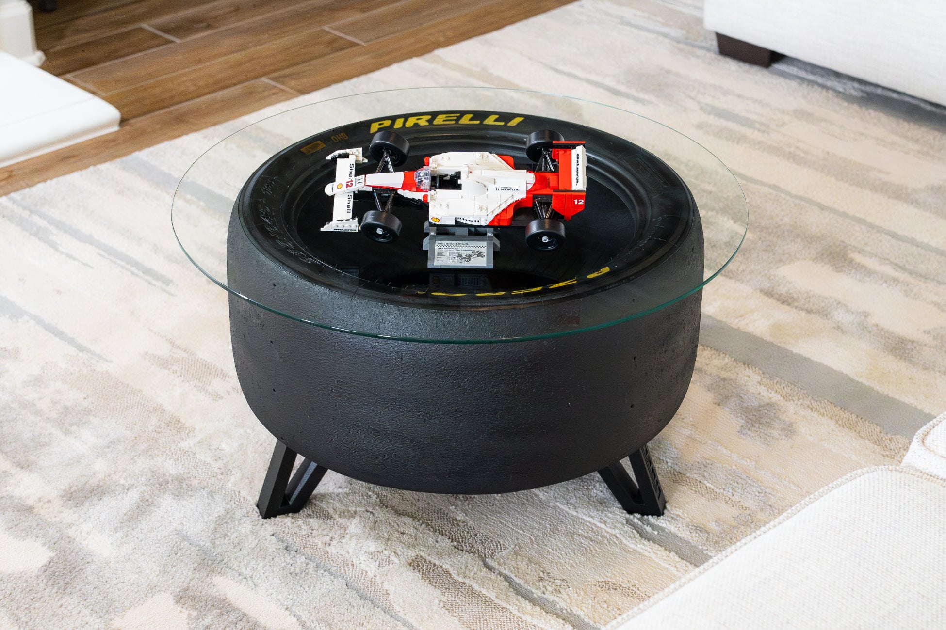 Custom Pirelli racing tire coffee table with round glass top displaying a red and white LEGO McLaren Formula 1 race car.