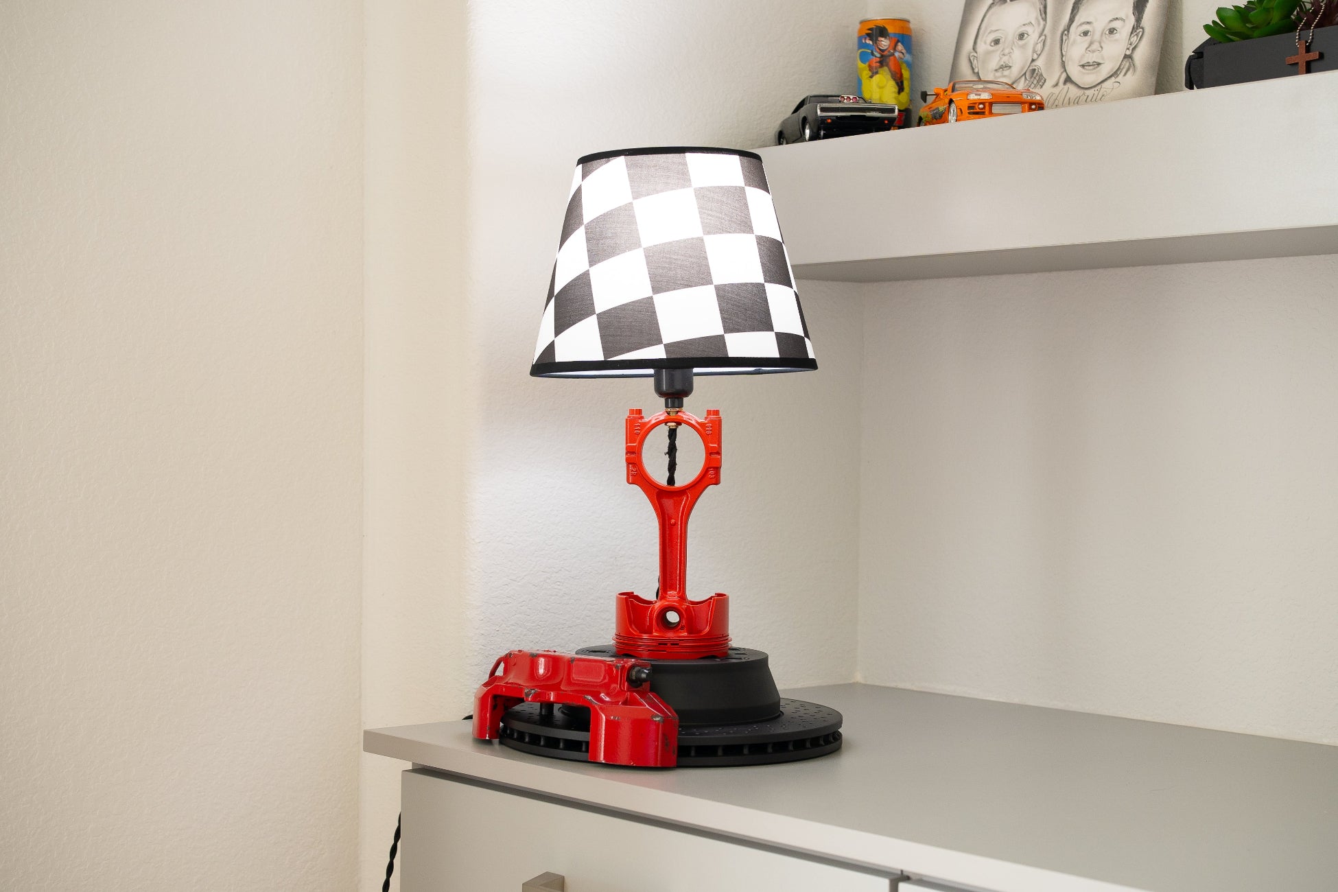 Handcrafted automotive desk lamp featuring a red Porsche piston stem, red brake caliper base, and checkered flag lampshade.