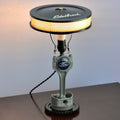 Ford piston lamp made from real car parts, featuring an upcycled piston and gear with a sandblasted metal finish for automotive decor.