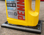Pennzoil jug lamp mounted on black stained oak base for stable display.