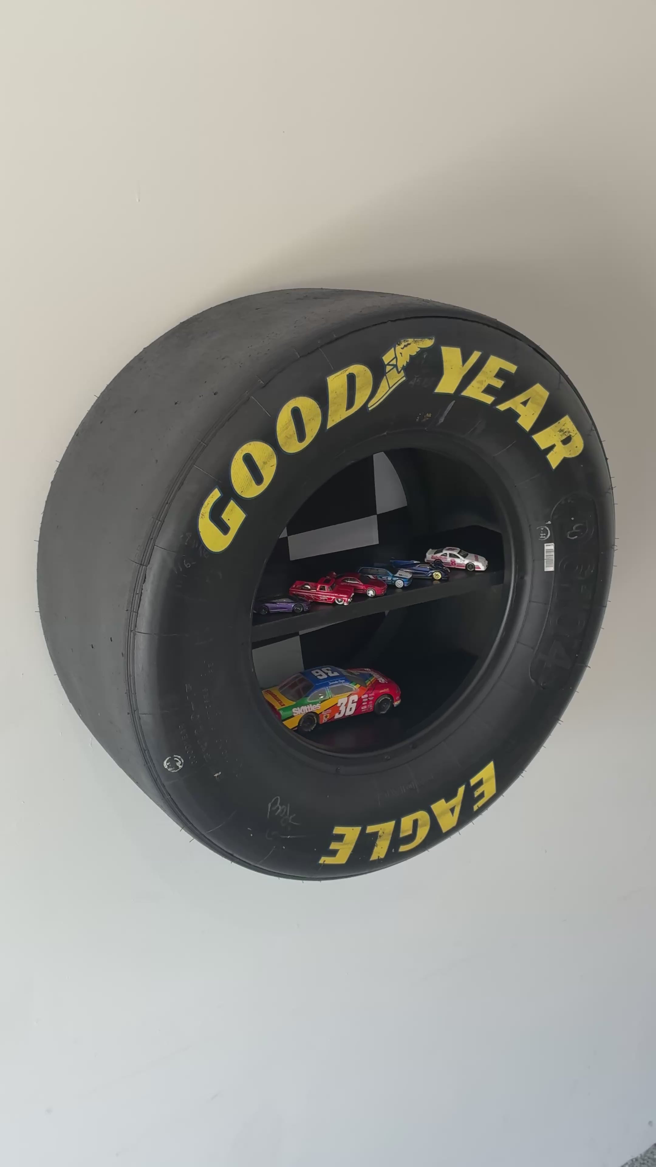 Wall shelf for racing memorabilia constructed from genuine NASCAR tire.