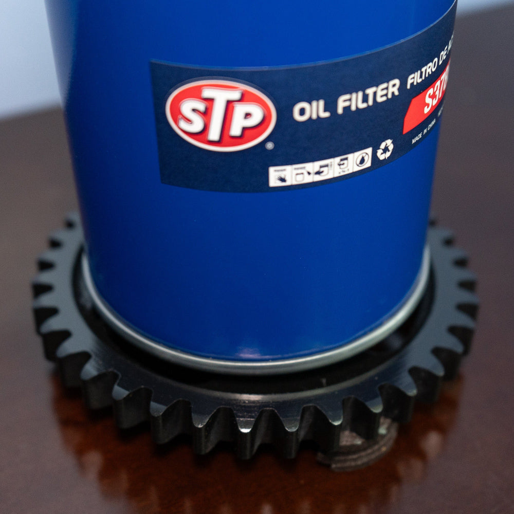 Lamp featuring an STP oil filter mounted on an upcycled gear base for rugged automotive character.
